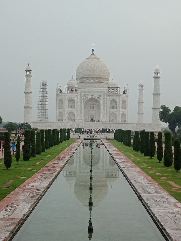 El Taj Mahal con gente caminando por el sendero del jardín.