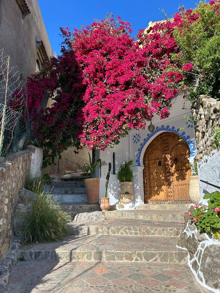 White building with flowers on an archway.