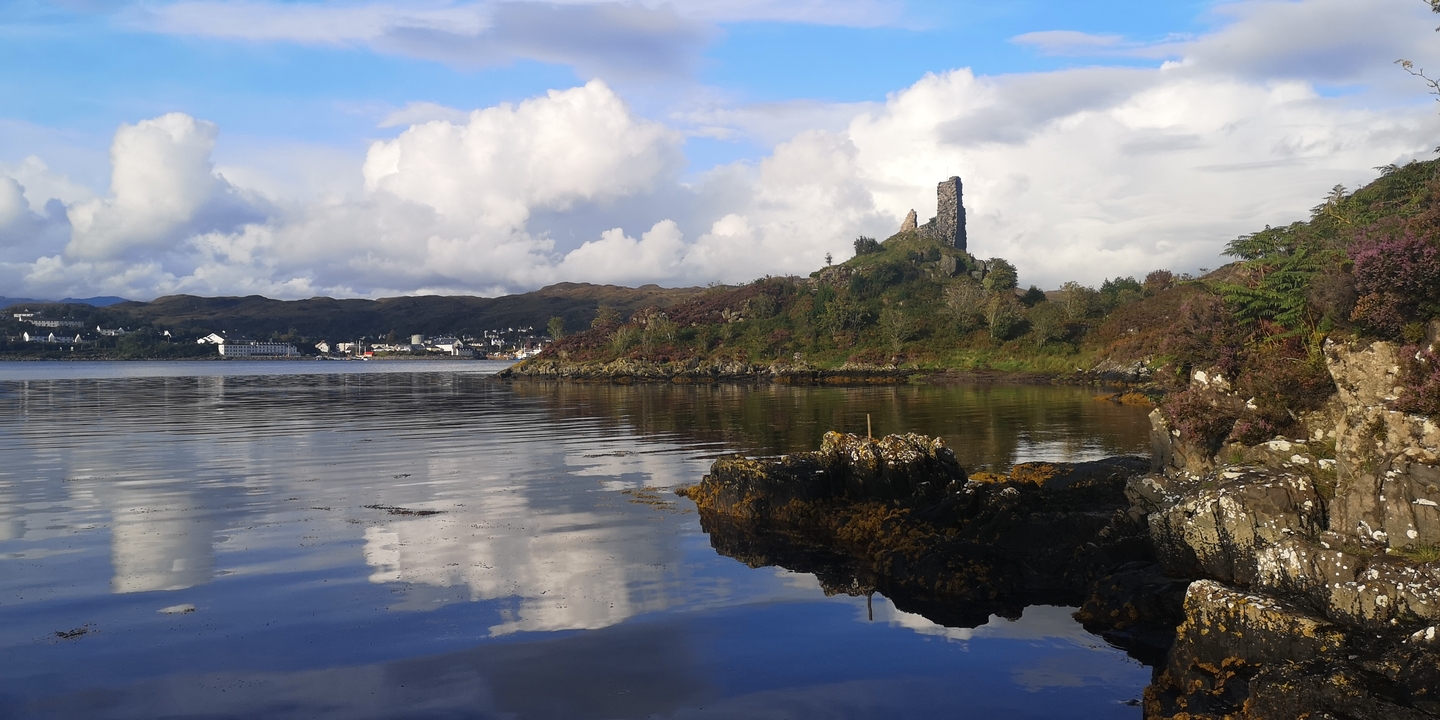 Rocky shoreline with ruins and cloudy sky.