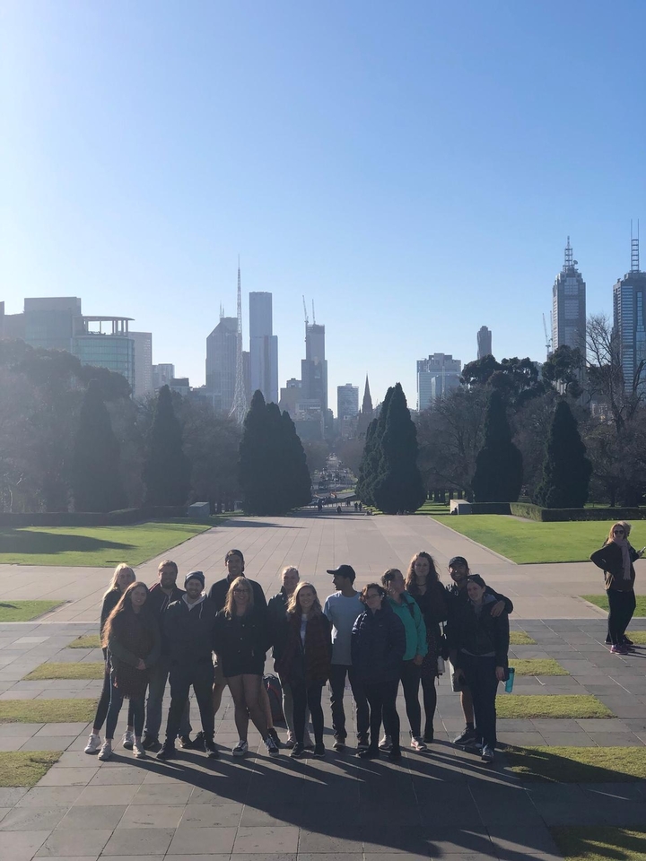 Un groupe posant dans un grand parc avec des gratte-ciel emblématiques de la ville en arrière-plan.