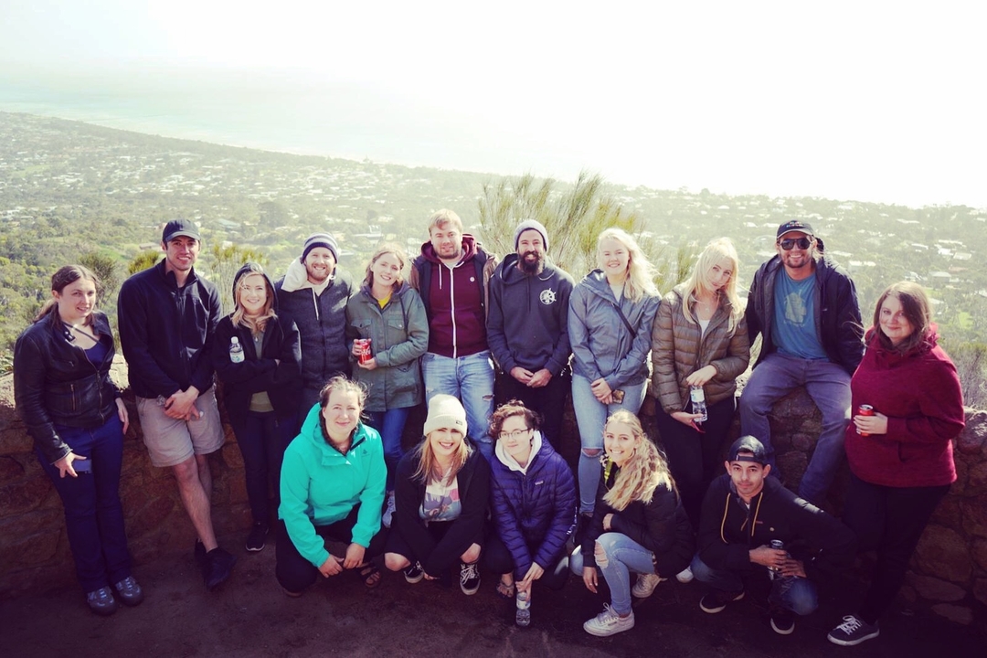 Grand groupe de personnes posant avec une vue sur une ville côtière en arrière-plan.