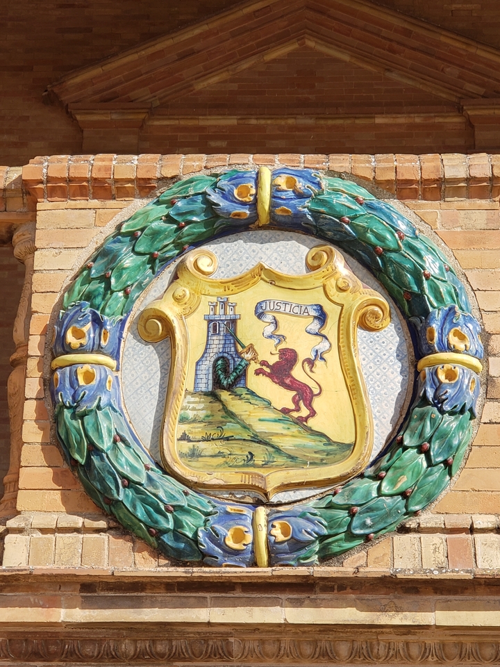 Plaque en céramique colorée avec un emblème représentant un lion et un château.