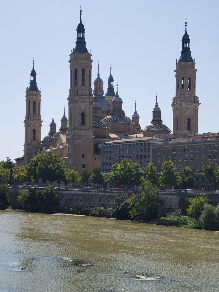 Vue d'une grande cathédrale avec plusieurs tours près de la rive du fleuve.