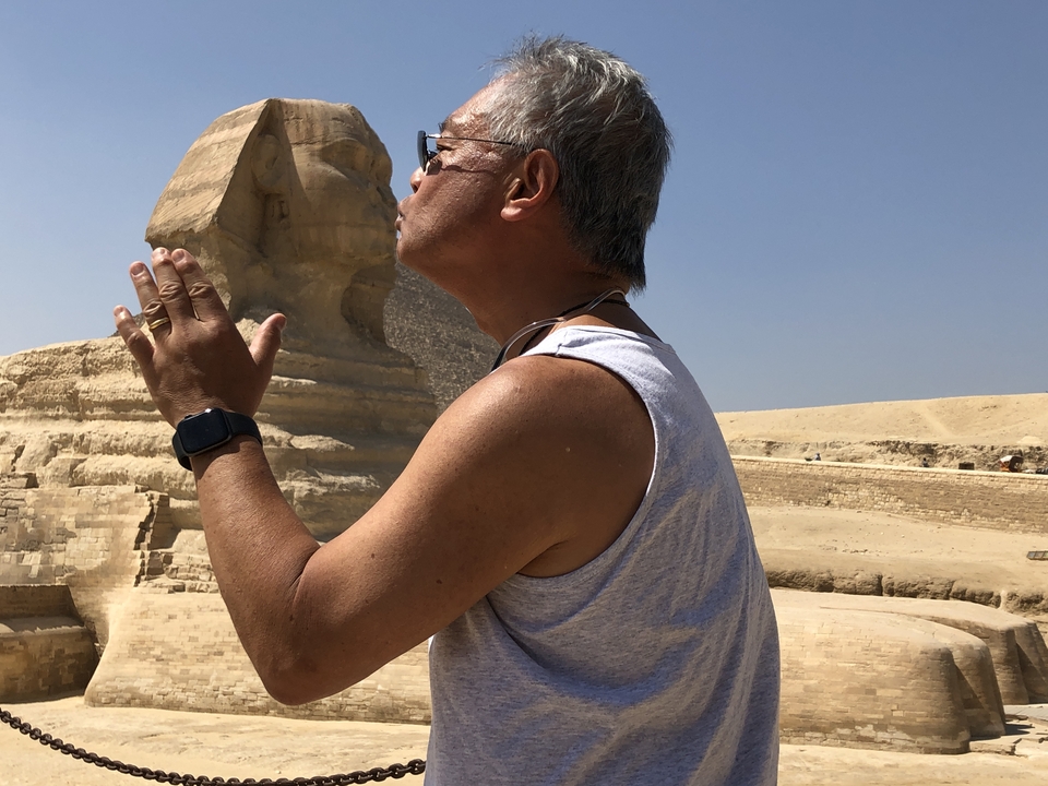 Tourist playfully interacting with the Great Sphinx.