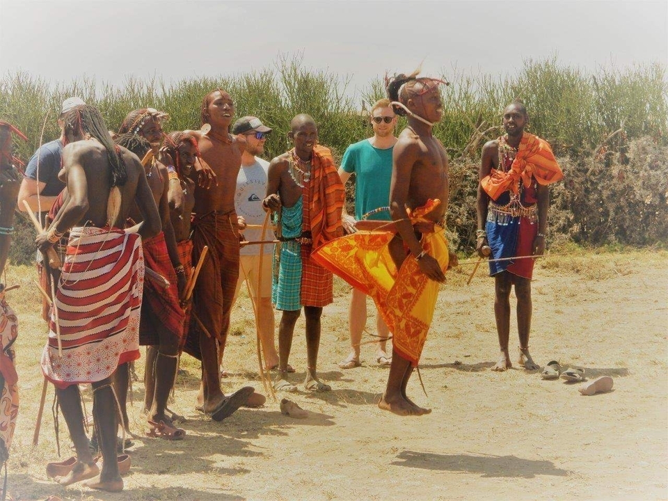 Des gens vêtus de tenues traditionnelles, certains sautant et d'autres regardant.