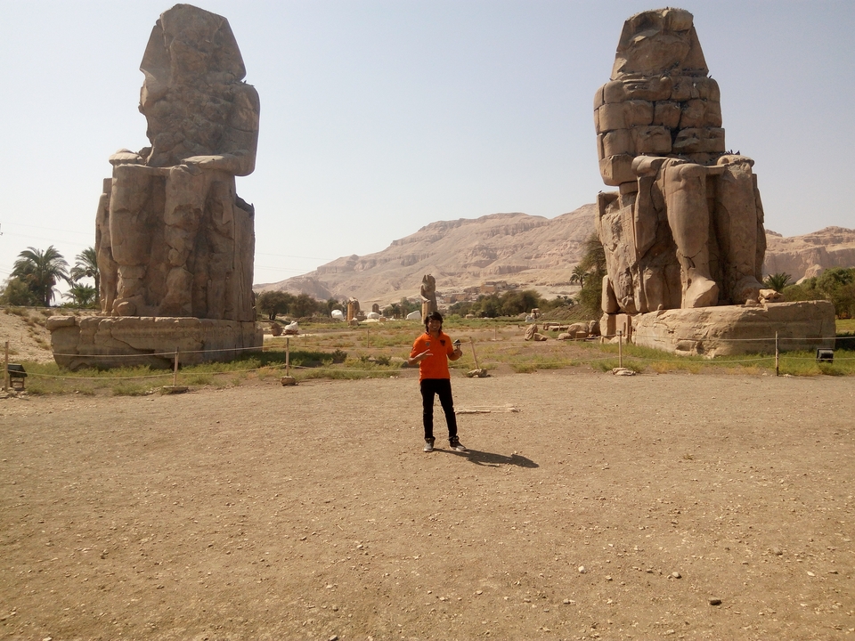 Personne debout entre deux statues géantes.