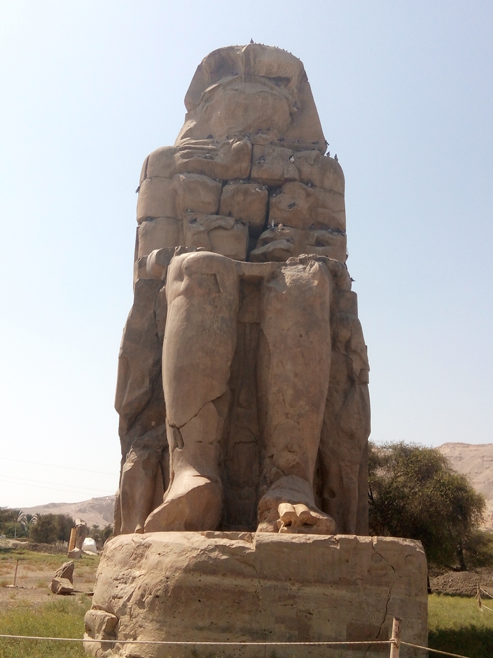 Statue antique colossale aux traits endommagés.