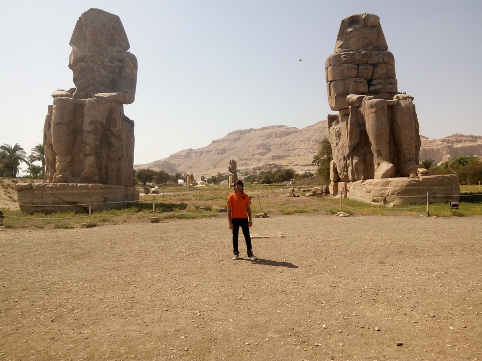 Personne debout entre deux statues massives.