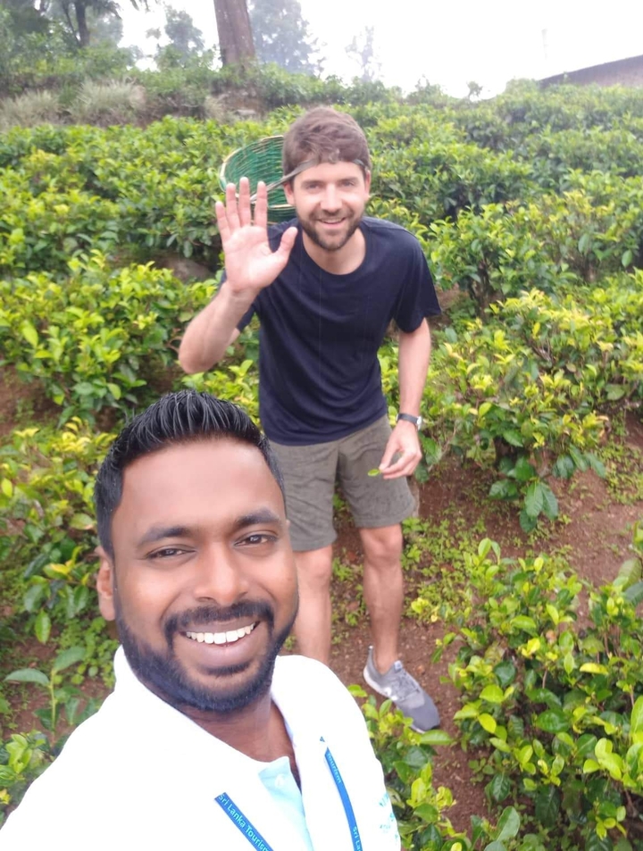 Two men in a nature setting, one waving to the camera.