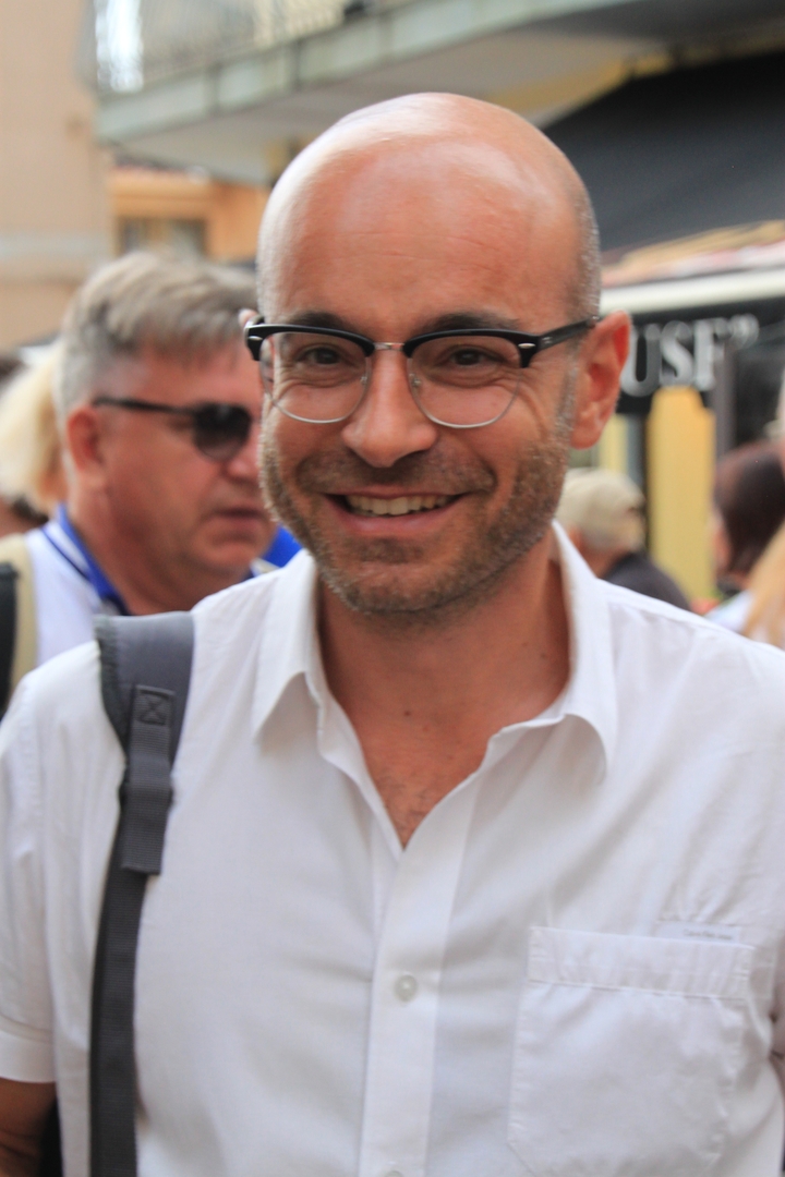 Close-up van een glimlachende persoon die een bril draagt.