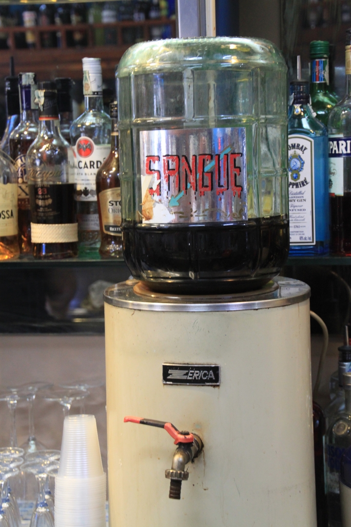 Barkaun met verschillende drankflessen en een pot met het label 'SANGUE'.