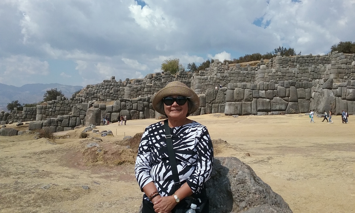 Femme assise près de structures en pierre anciennes.
