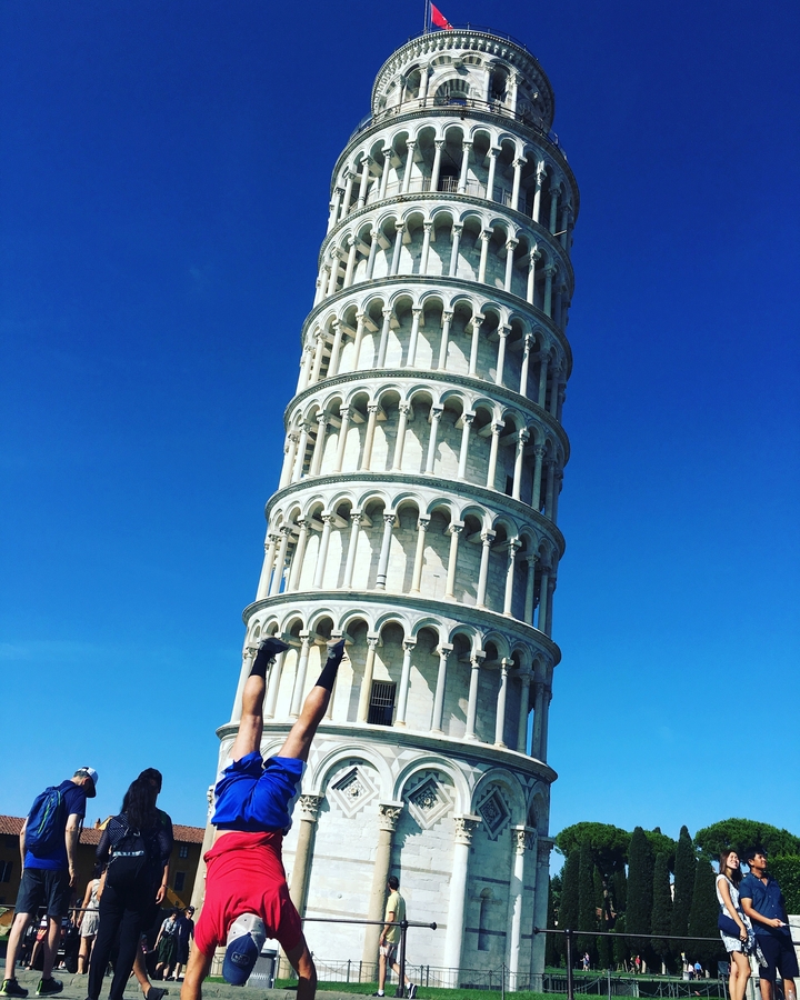 Person humorously pretending to hold up the Leaning Tower of Pisa.