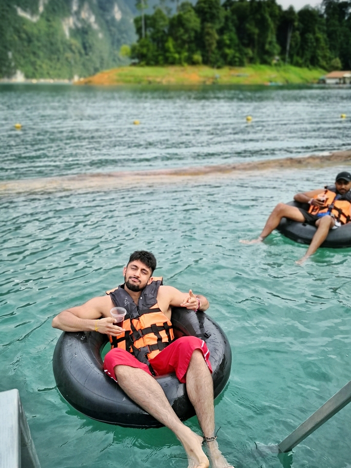 Two men floating in tubes on clear water.