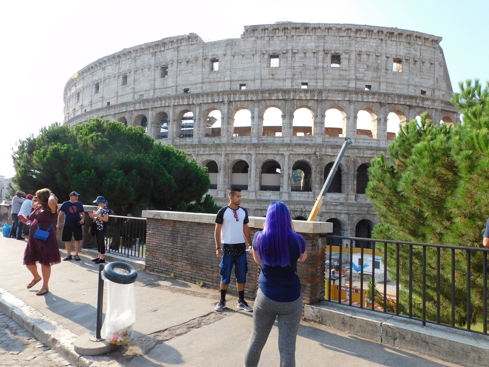 Tourists near the Colosseum with trees and sky in the background.