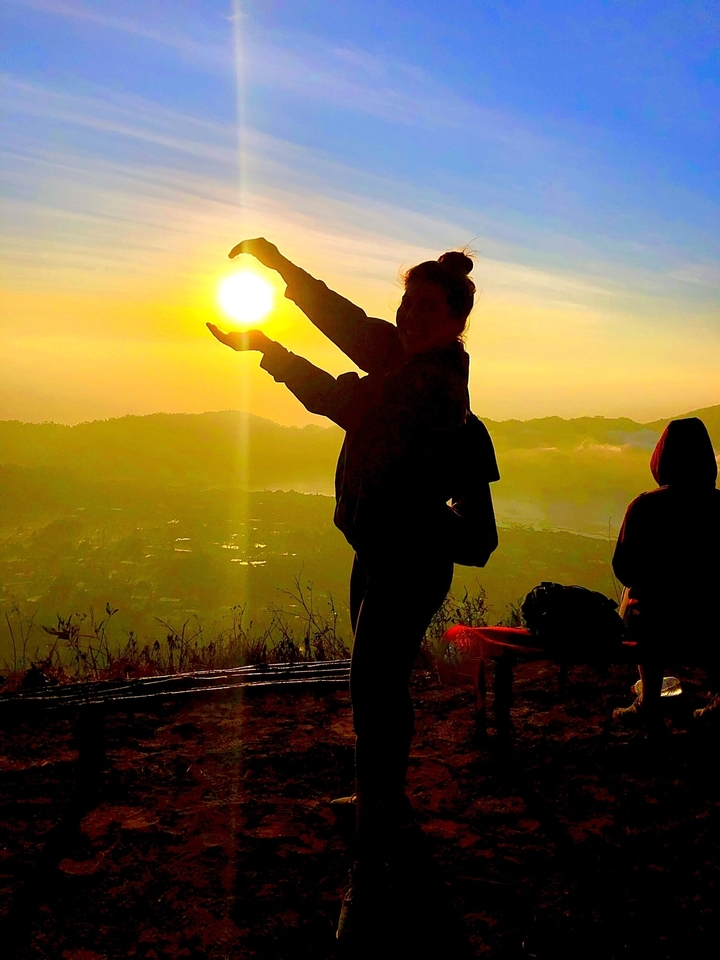 Silhouette d'une personne tenant le soleil pendant le lever du soleil au-dessus d'une vallée