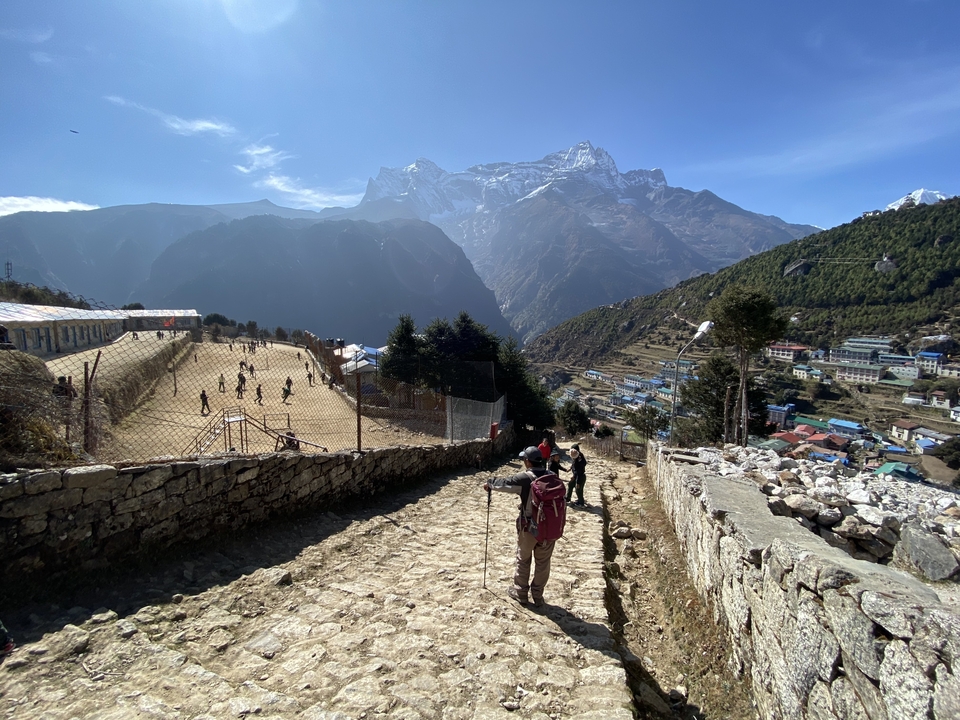 Hikers on a rocky path overlooking a mountainous landscape.
