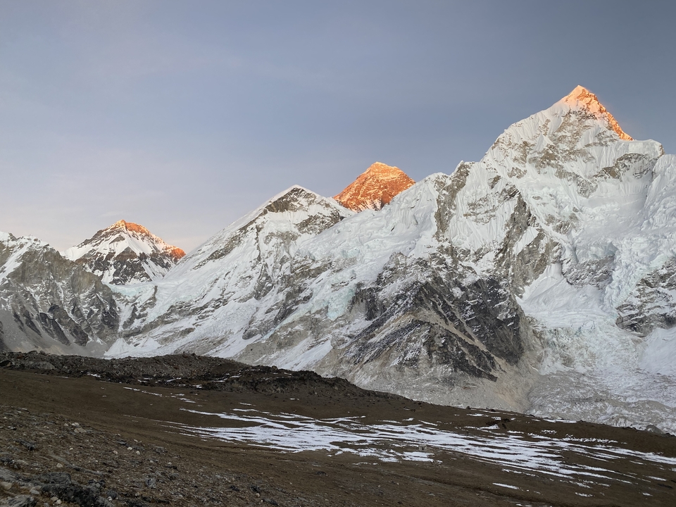 Alpenglow on snow-capped mountains in a vast landscape.