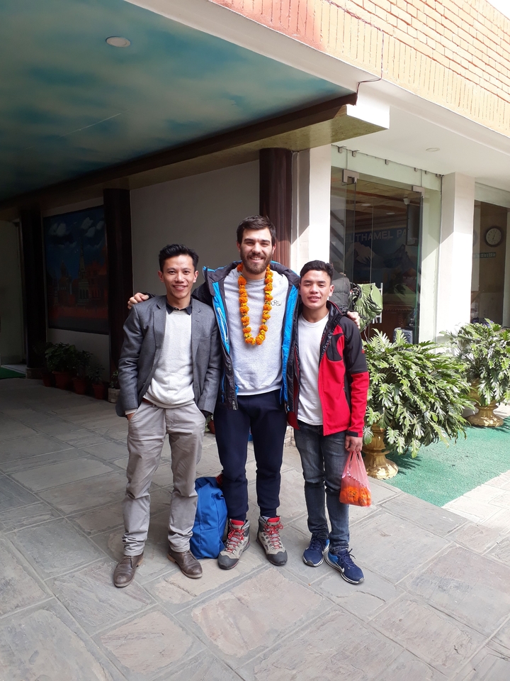 Three people smiling and posing indoors with plants.