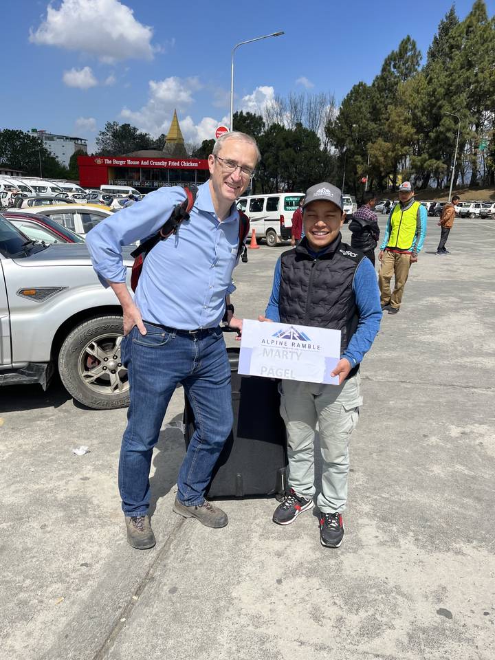 Two travelers at an airport, one holding a welcome sign.