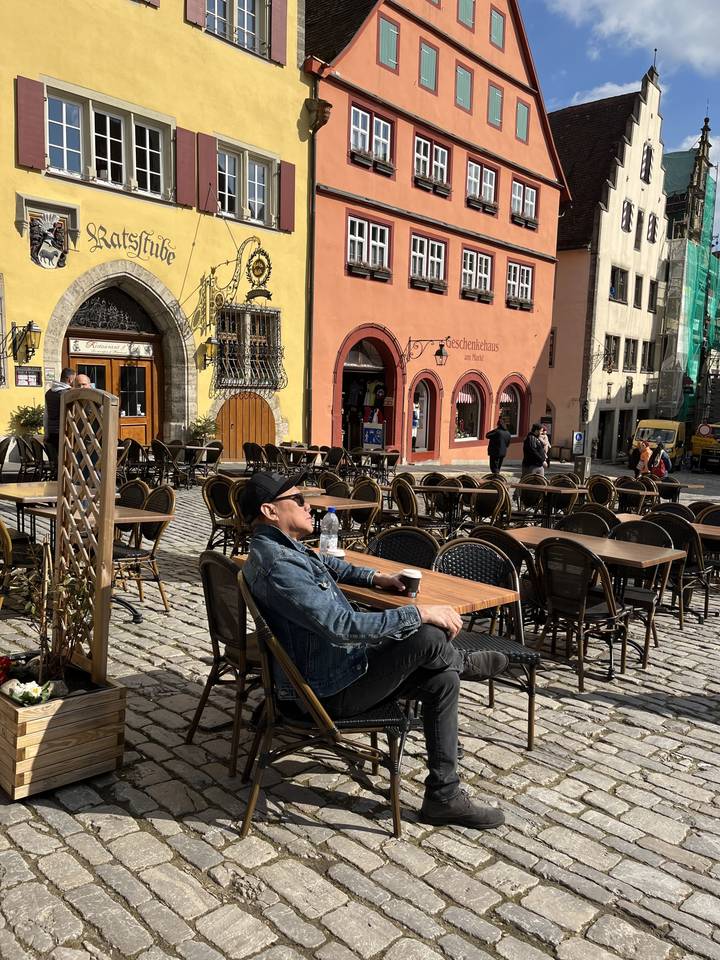 Person sitting at an outdoor cafe in a colorful street setting.
