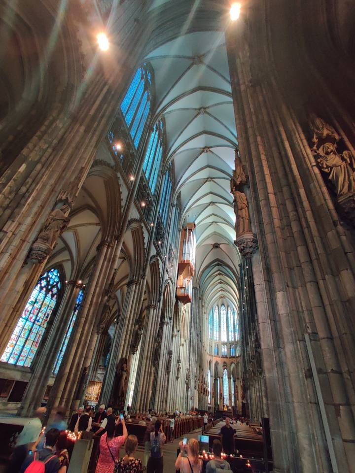 Vue intérieure de la cathédrale de Cologne avec ses plafonds voûtés et ses vitraux.