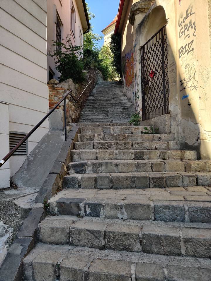 Des marches en pierre menant vers le haut avec des graffitis sur le côté.
