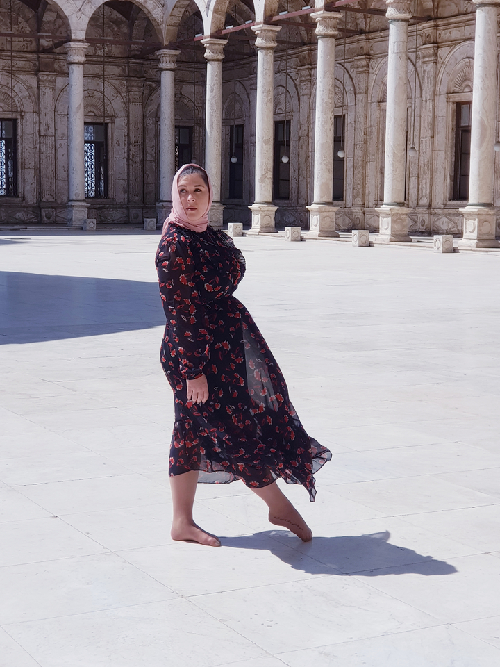 Femme posant devant des colonnes architecturales.