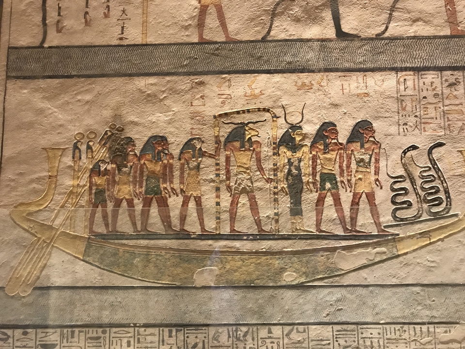 Représentation hiéroglyphique d'Égyptiens ramant dans un bateau sur une peinture murale antique.