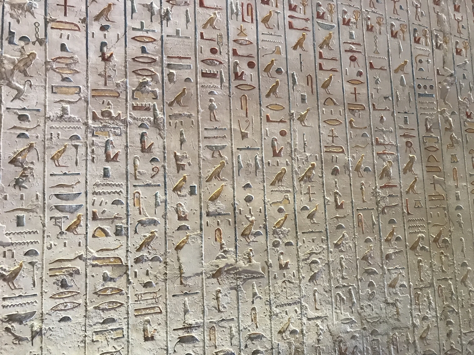 Hiéroglyphes égyptiens complexes gravés dans un mur.