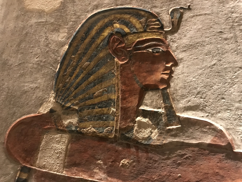 Portrait coloré sculpté d'un pharaon égyptien sur une surface de pierre.