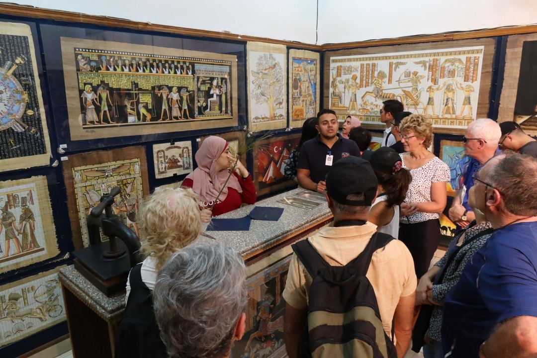 Groupe de touristes dans une galerie de papyrus avec de l'art égyptien.