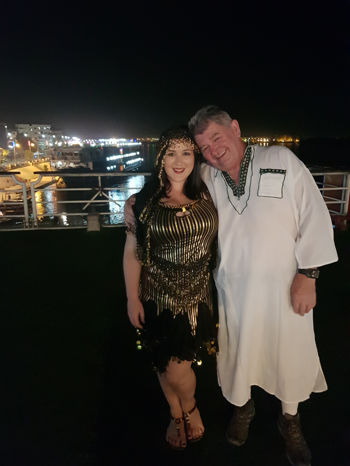 Deux personnes en tenue traditionnelle avec des lumières de la ville en arrière-plan.