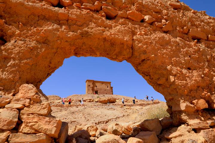Historic rock arch framing a small building.
