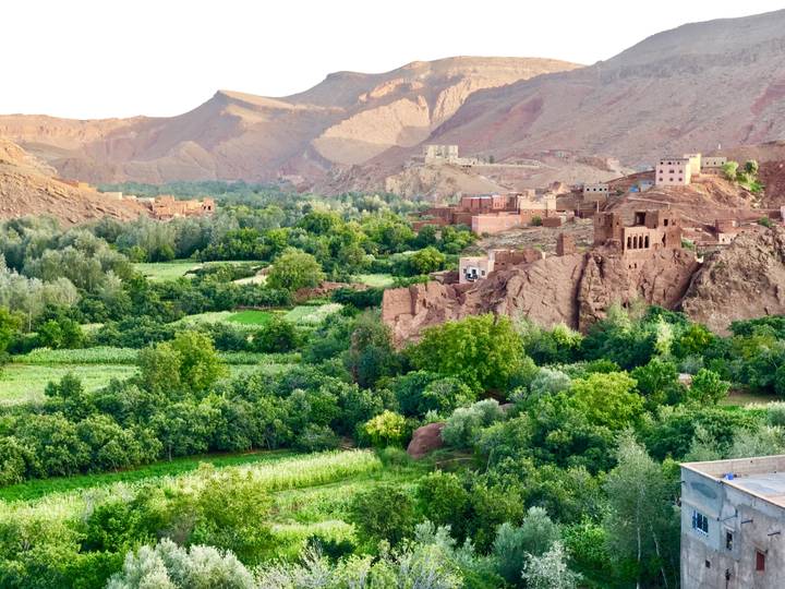 Green valley with a small village and mountain backdrop.