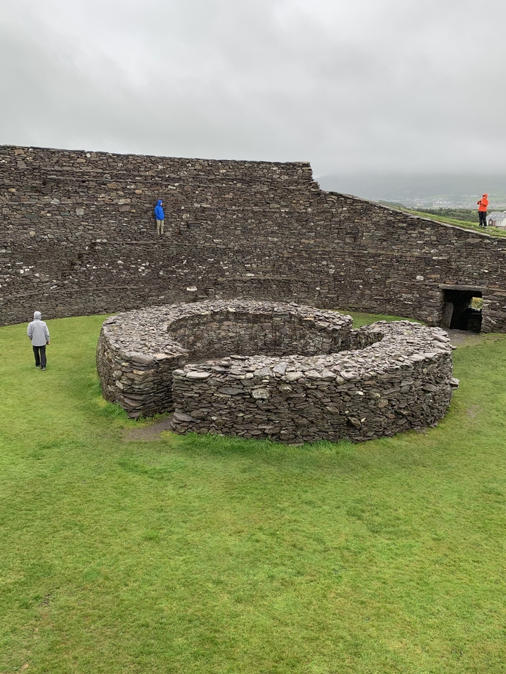 Circular stone fort in a grassy area.