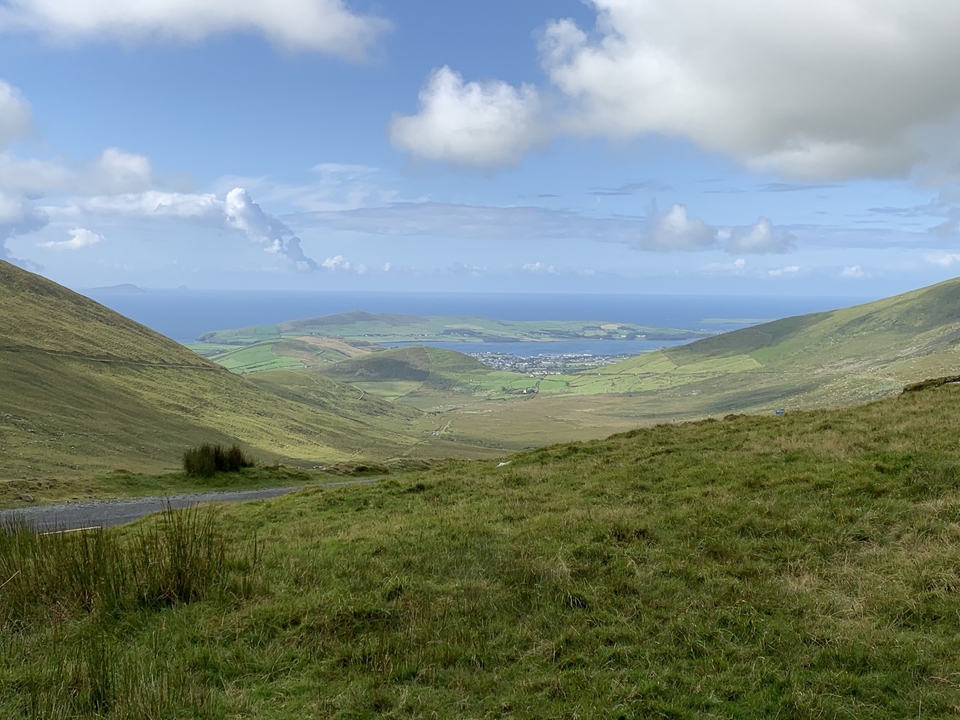 Panoramic view of a green valley with ocean in the background.
