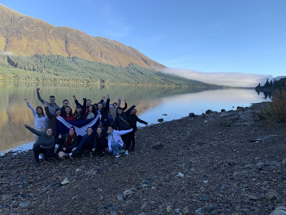 Group celebrating by a lake with mountains.