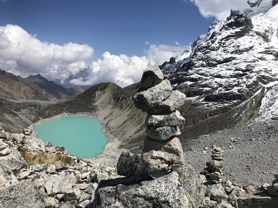 Stacked stones by a turquoise glacial lake in the mountains.