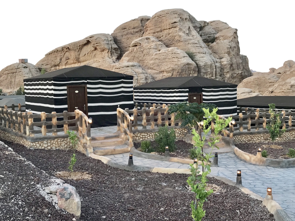 Encampment with striped tents and rocky mountains.