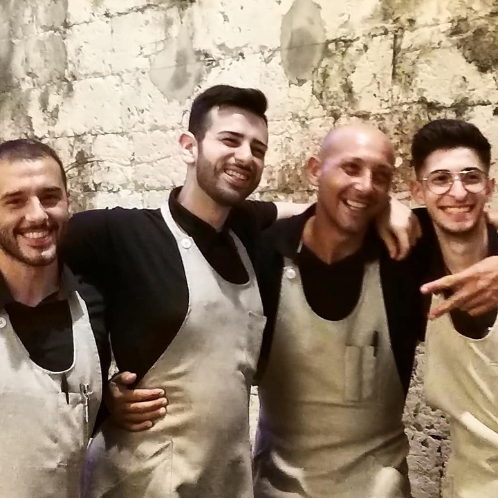Group of people smiling in front of a stone wall.
