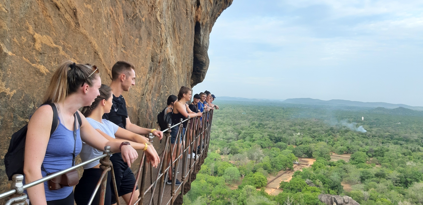 Large group climbing the Lion Rock with vast views below.