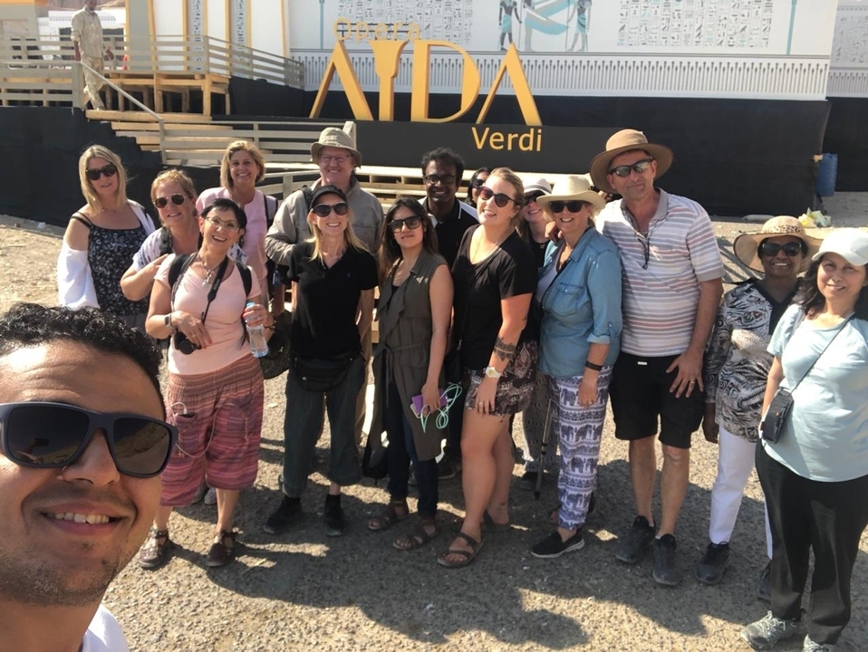Groupe de touristes posant devant un navire de croisière nommé AIDA Verdi.