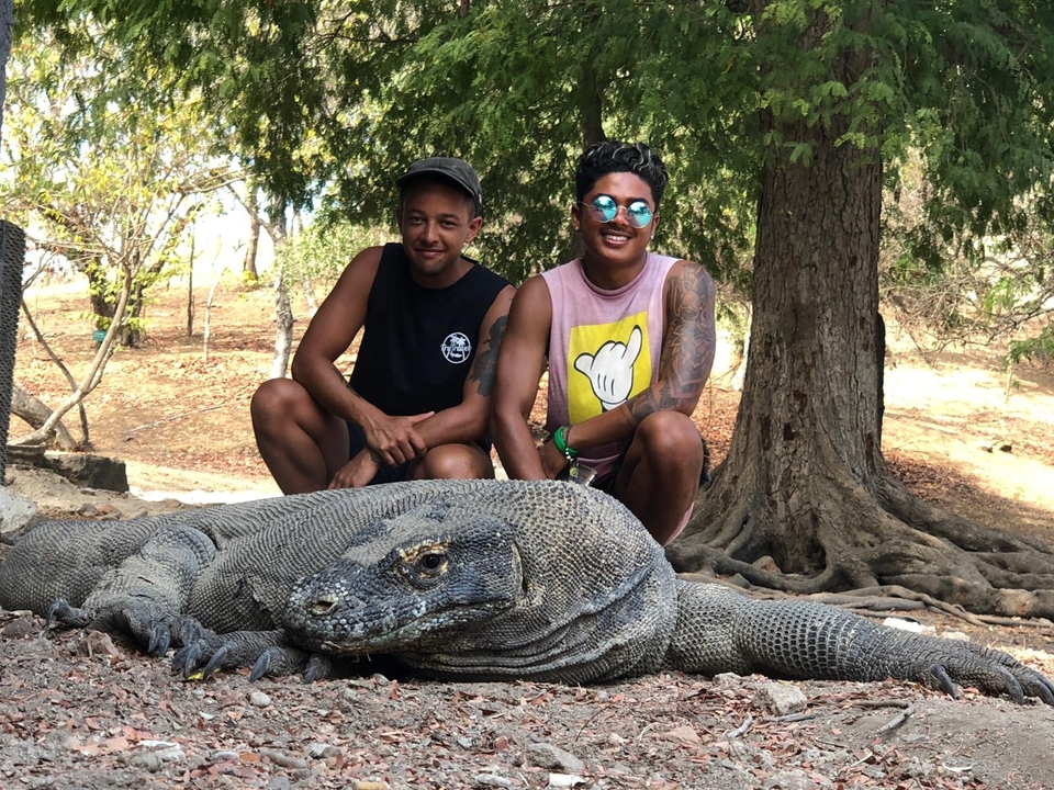 Deux personnes posent avec un grand dragon de Komodo.