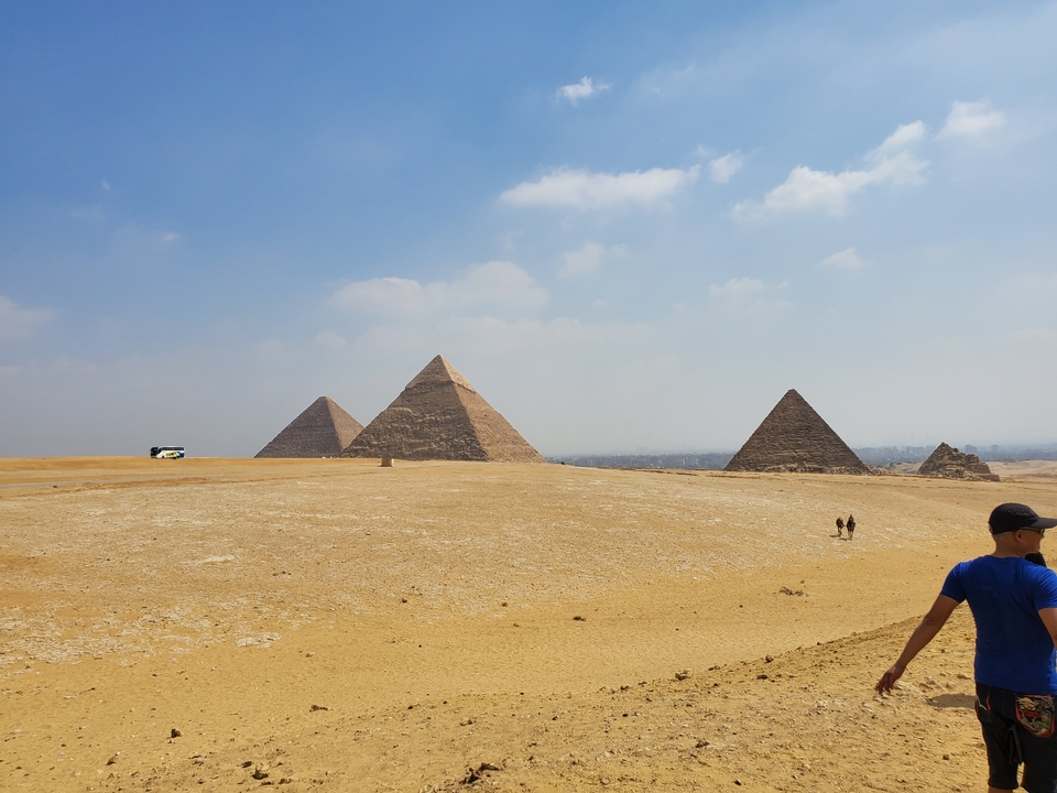 Giza pyramids with people walking in the desert.