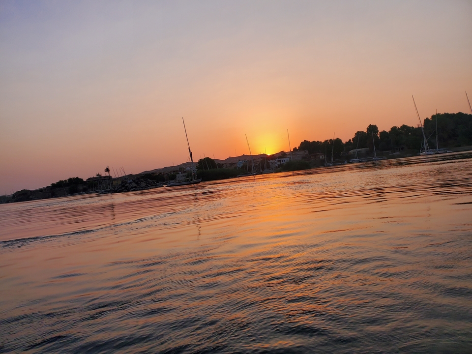 Sunset over a river with boats in the distance.