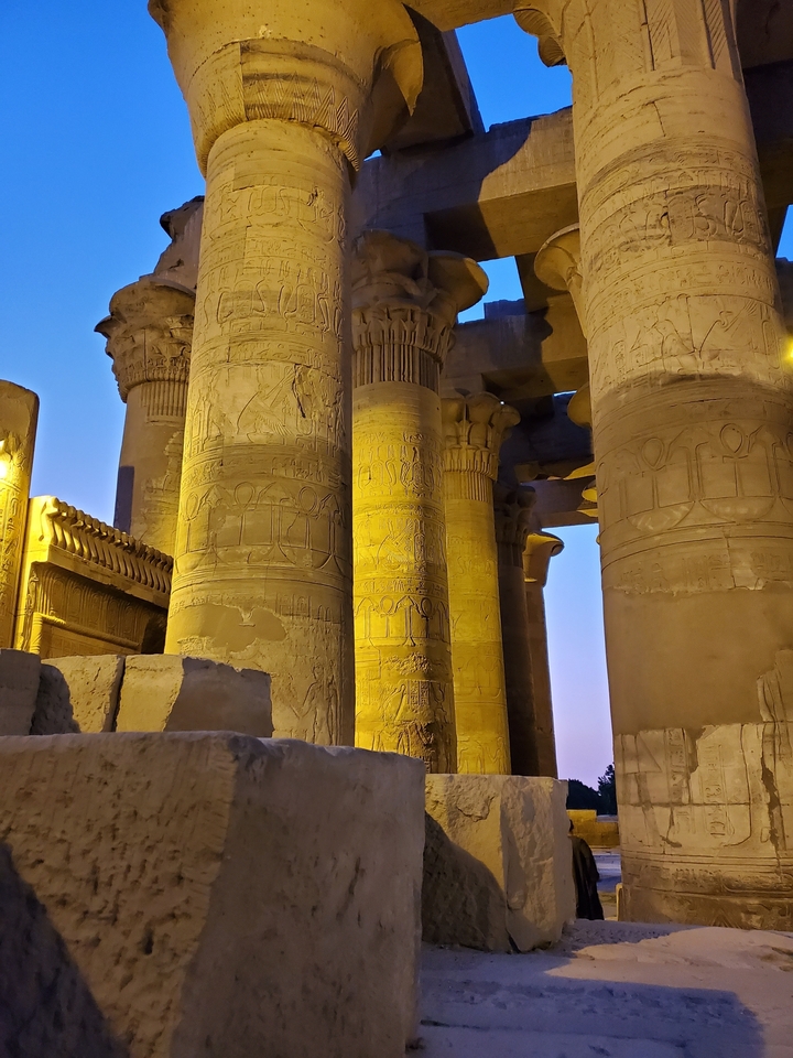 Illuminated ancient columns with carvings at night.