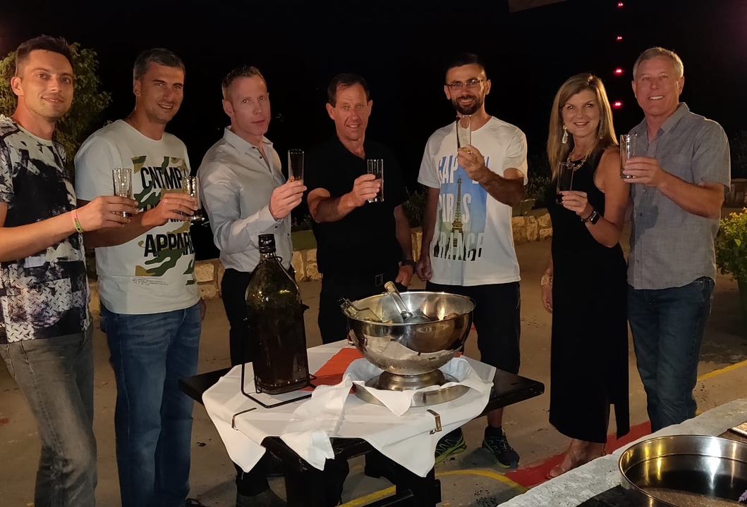 Group of friends toasting at a table with drinks and snacks.