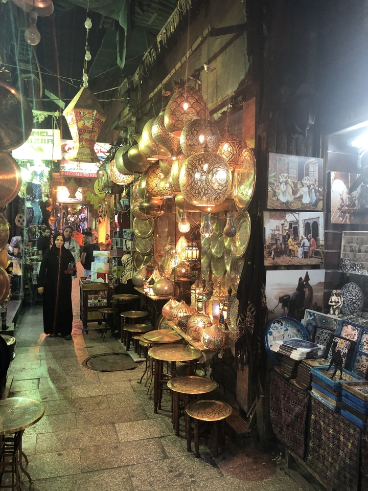 Shop with various traditional lamps and decorations, a woman walking past.