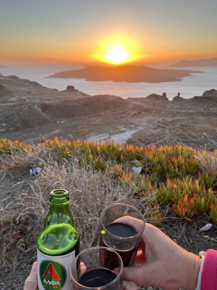 Beer bottle on a grassy hill overlooking a sunset.